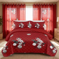 Red and white floral quilted bedspread with matching pillow shams and coordinating curtains in a bedroom.