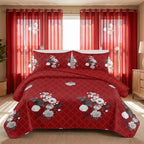 Red and white floral quilted bedspread with matching pillow shams and coordinating curtains in a bedroom.